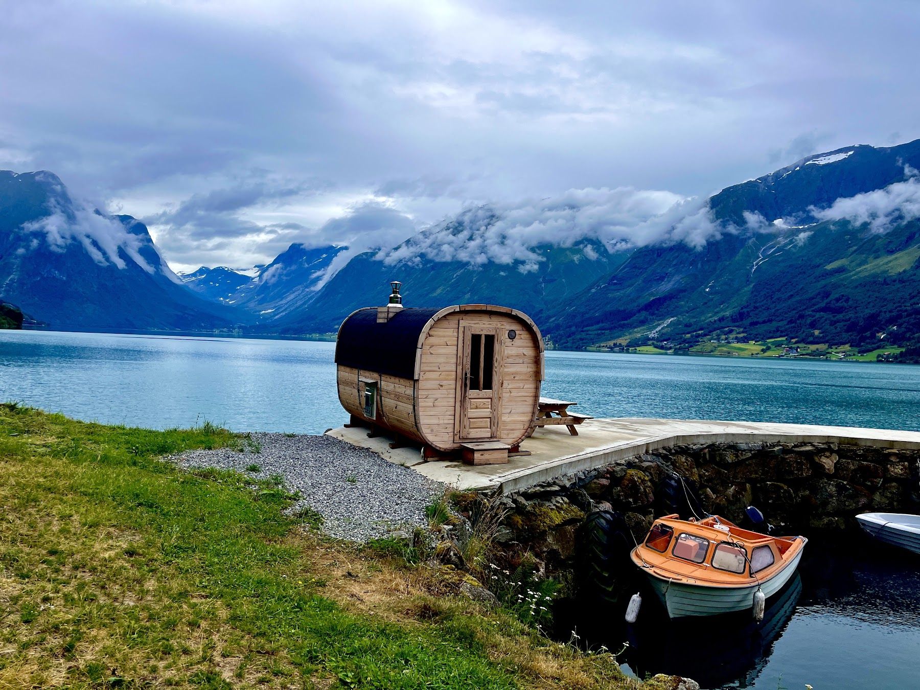 Saunaen på Flo Brygge ved vannet, med fjell og skyer